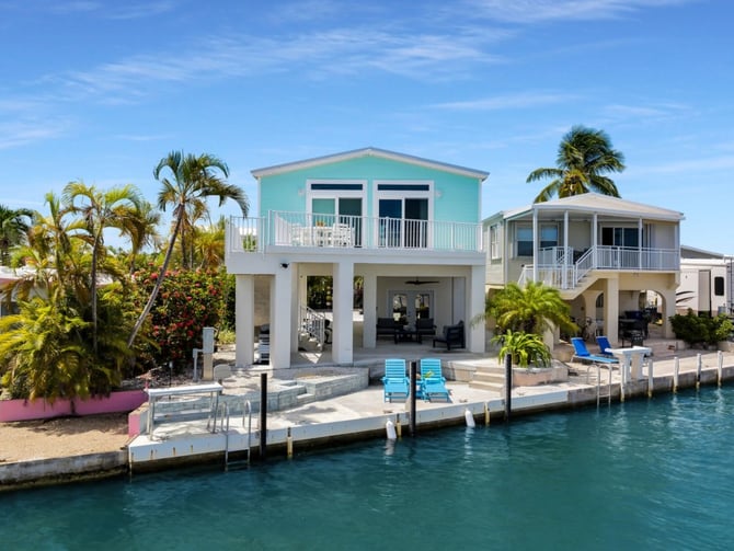 Teal waterfront home with dock and blue loungers