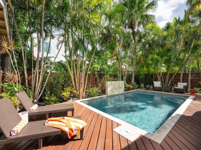 Private pool surrounded by tall tropical palms and wood deck