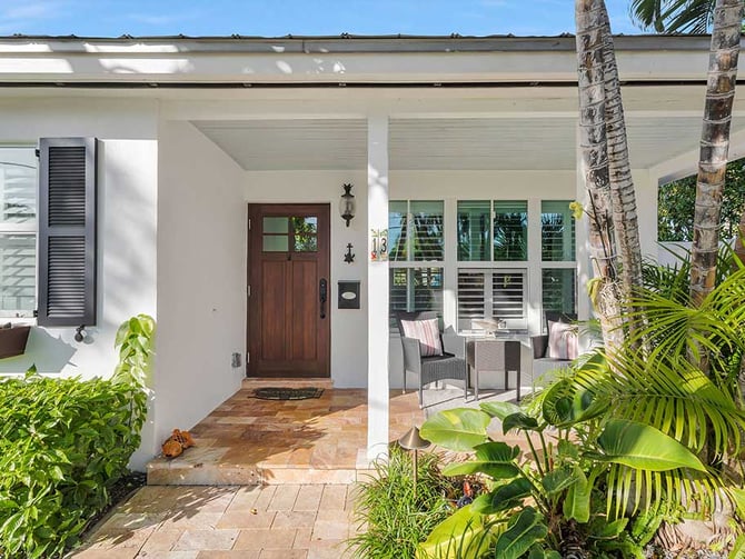 Welcoming front entry with porch seating and tropical garden