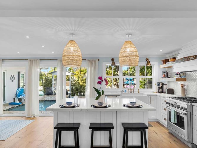 Bright white kitchen with wicker pendant lights and pool view